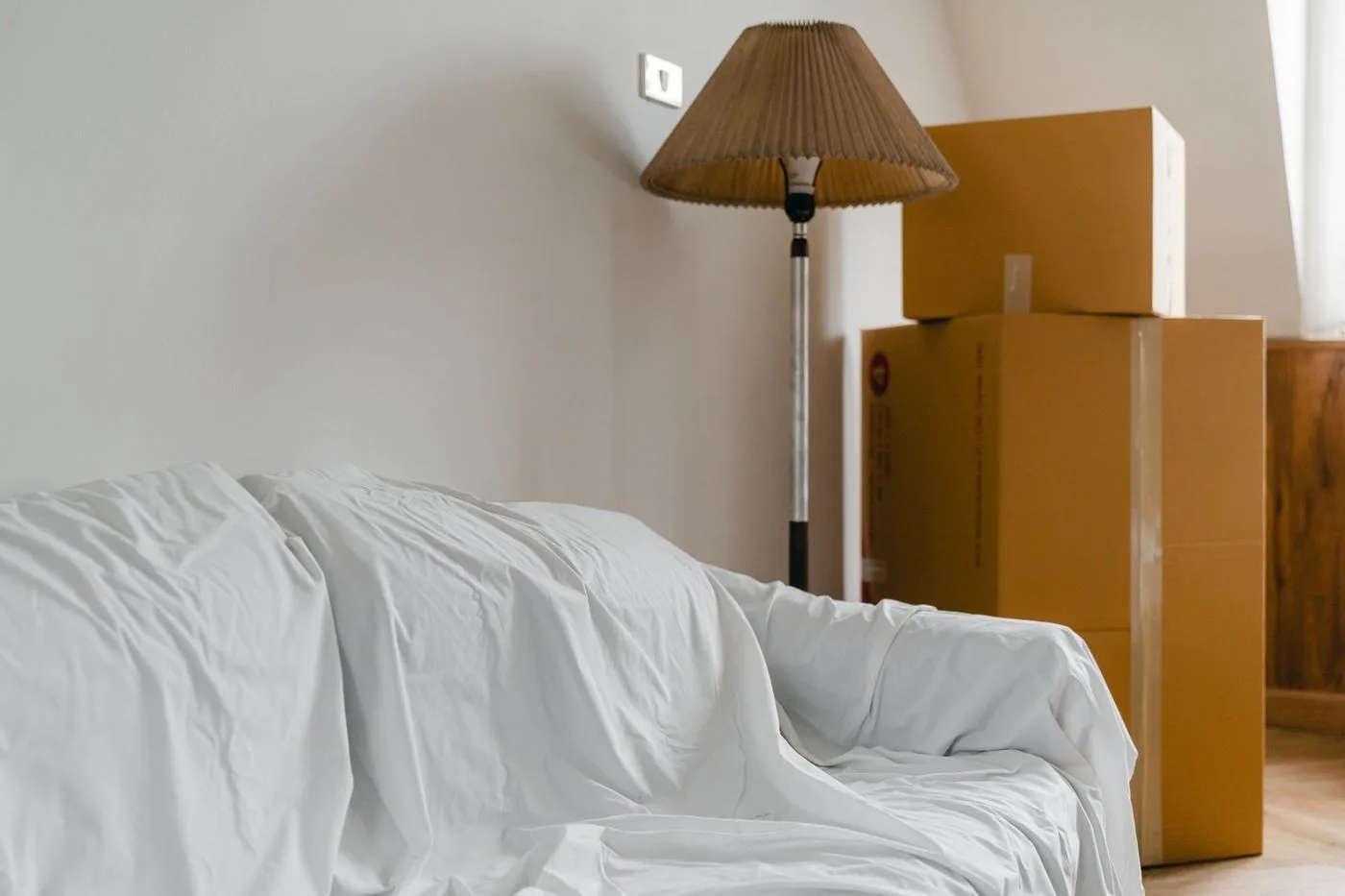 Canapé recouvert d'un drap et cartons de déménagement empilés, prêts à être stockés pendant les travaux